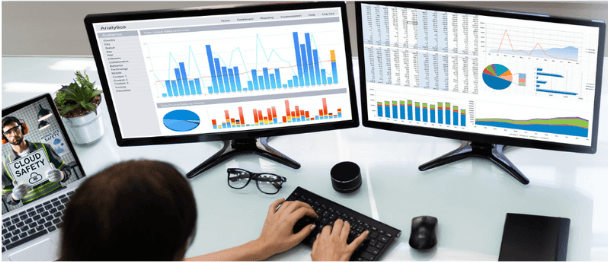 Analista em frente a dois monitores com dashboards de gráficos da Cloud Safety